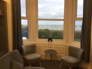 um quarto com duas cadeiras, uma mesa e uma janela em Ashburnam Guest House em Hornsea