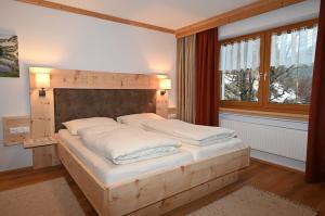 Schlafzimmer mit einem Bett mit einem Kopfteil aus Holz und einem Fenster in der Unterkunft Appartement Panorama NEU in Biberwier