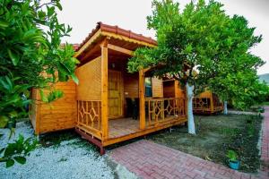 a wooden cabin with a tree in front of it at Eliz Apart & Bungalow in Kumluca