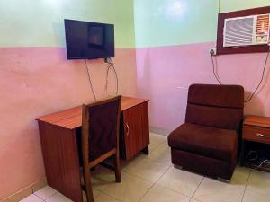 een kamer met een bureau, een stoel en een televisie bij Suofega Hotel and Suites in Ughelli