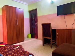 een woonkamer met een tv en een aantal houten kasten bij Suofega Hotel and Suites in Ughelli