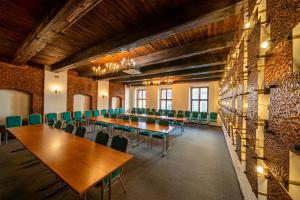 uma sala de conferências com mesas de madeira e cadeiras verdes em Hotel Gromada Toruń em Toruń