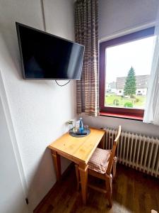 Habitación con mesa de madera y TV en la pared. en Landgasthaus Sternen en Kehl am Rhein