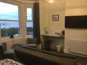 a living room with a couch and a window at Ashburnam Guest House in Hornsea