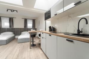 een keuken met een wastafel en een bed in een kamer bij Toress Apartamenty Brama Portowa in Szczecin