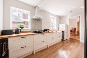 a kitchen with white cabinets and a wooden floor at Guest Homes - Sherrington Road Abode in Ipswich