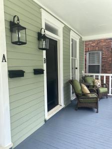 um alpendre com duas cadeiras de vime numa casa em Harmony House em Savannah