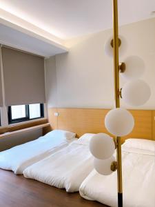 台南梧同包棟民宿La Petite Maison I Entire House BnB I 寵物友善 I 國旅卡 I 出差商旅可報帳 I 電動麻將 I NETFLIX I Nintendo Switch I MOD I一軒家貸切的卧室里有一张白色的大床和一盏灯