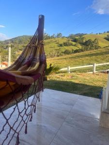 a hammock on a fence with a view of a field at Pousada do valle in Monte Verde