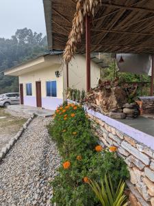 una casa con una pared de piedra y flores delante de ella en Firfirey Organics- Regenerative Farm Retreat, en Bathāla