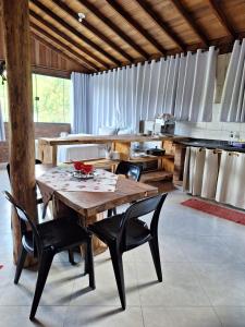 a kitchen with a wooden table and black chairs at Aconchego da Beth in Camanducaia