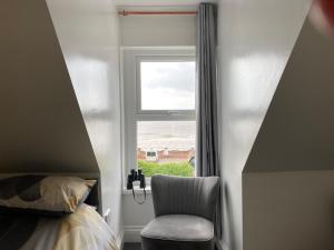 a bedroom with a chair next to a window at Ashburnam Guest House in Hornsea