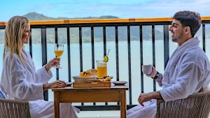 a man and woman sitting at a table with drinks at Catalina Hotel in Ubatuba