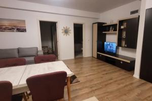 un soggiorno con tavolo, divano e TV di Apartament Sânpetru-Brașov a Sînpetru