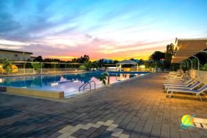 a swimming pool with a sunset in the background at Village Due Elle in Marina di Schiavonea
