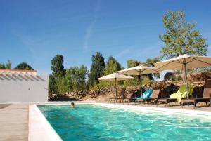 a person in a swimming pool with chairs and umbrellas at Casa dos Edras in Miranda do Douro