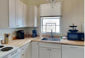 uma cozinha com armários brancos, um lavatório e um micro-ondas em Harmony House em Savannah