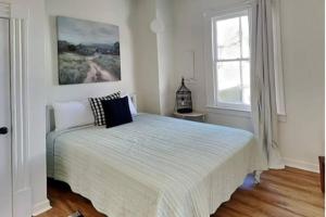 um quarto branco com uma cama e uma janela em Harmony House em Savannah