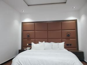 a bedroom with a large white bed with a brown headboard at Hotel Thirty Five in Lagos