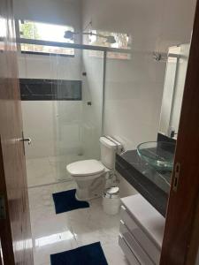 a bathroom with a toilet and a glass shower at Casa Parque Aquático in Andradina