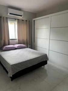 Un dormitorio con una cama con almohadas moradas y una ventana en Casa Parque Aquático, en Andradina