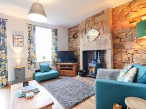 un soggiorno con divano blu e parete in pietra di 3 Sunnyside Terrace a Matlock