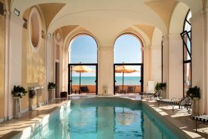 kryty basen w budynku z oknami i basen w obiekcie La Posta Vecchia Hotel w mieście Ladispoli