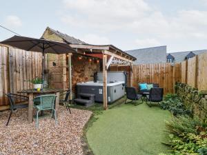 a backyard with a grill and chairs and an umbrella at 3 Sunnyside Terrace in Matlock