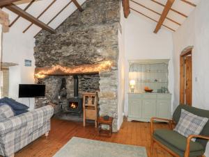 a living room with a stone wall with a fireplace at Pant y Crintach in Amlwch