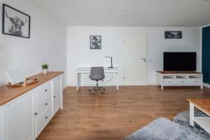 ein Wohnzimmer mit einem Schreibtisch und einem TV in der Unterkunft Ferienwohnung "Kapellmeister" mit Klimaanlage in allen 4 Schlafbereichen, großes Wohnzimmer mit Smart TV und Big Sofa in Magdeburg