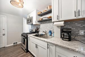 a kitchen with white cabinets and a sink and a stove at The Downtown Delight - New Corporate Apt Downtown in Grand Rapids