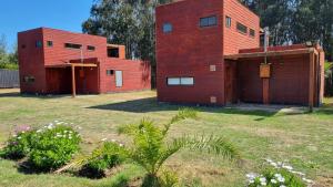 two red brick buildings in a yard with flowers at Maria Clara in Navidad