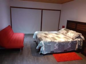 - une chambre avec un lit et une chaise rouge dans l'établissement Maria Clara, à Navidad