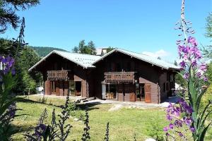 a large wooden house in a field with flowers at CASA-Forêt Blanche splendid chalet 13p in Risoul