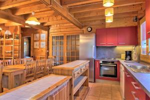 cocina con armarios rojos y techo de madera en CASA-Forêt Blanche splendid chalet 13p, en Risoul