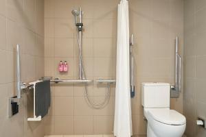 y baño con ducha, aseo y cortina de ducha. en Moxy Birmingham NEC, en Bickenhill
