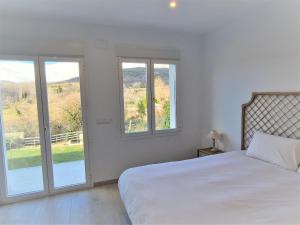 a white bedroom with a bed and two windows at Villa de lujo en Jarandilla in Jarandilla de la Vera