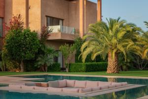 a house with a palm tree and a swimming pool at Maison Kenoosha Boutique Hotel & Spa in Marrakesh