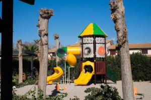 un parque infantil con tobogán en un parque con árboles en Maison de vacances plein pied tout confort 200m plage, en Portiragnes
