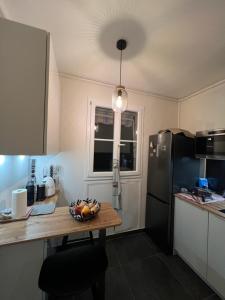 eine Küche mit einem Tisch und einem schwarzen Kühlschrank in der Unterkunft 70m2 Cosy Apartment Daguerre in Paris