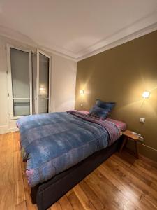 um quarto com uma cama grande e um cobertor azul em 70m2 Cosy Apartment Daguerre em Paris
