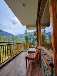 a balcony with a bench and a view of the mountains at The Woodpecker Inn Jibhi in Jibhi