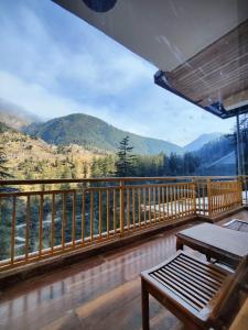 a balcony with a table and a view of mountains at The Woodpecker Inn Jibhi in Jibhi