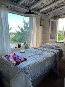 un letto in una camera con una grande finestra di La Peregrina - Posada a La Pedrera