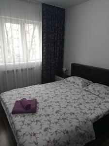 a bed with a purple hat on top of it at Penti Apartament in Suceava