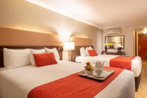 a hotel room with two beds and a tray with flowers at Stanza Hotel in Mexico City