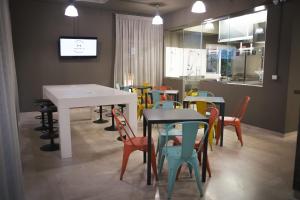 a dining room with tables and chairs and a kitchen at Hostelò - Luxury Hostel in Palermo