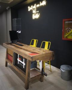 stół z dwoma żółtymi krzesłami i komputerem w obiekcie Hostelò - Luxury Hostel w mieście Palermo