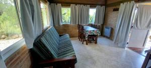 a room with a table and chairs and windows at Cabañas & Suites "No es Fácil" in Villa Yacanto