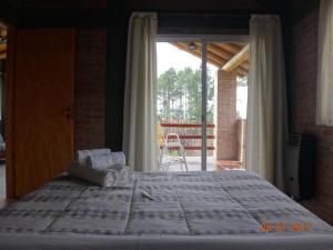 a bedroom with a large bed and a balcony at Cabañas & Suites "No es Fácil" in Villa Yacanto +18 photos